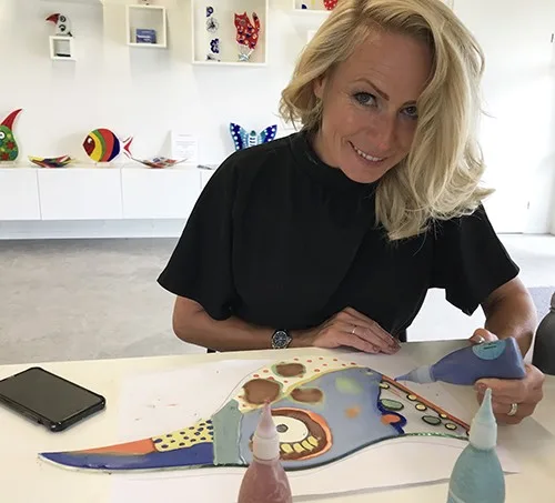 Deelnemer schildert met glaspoeder op een glazen vogel