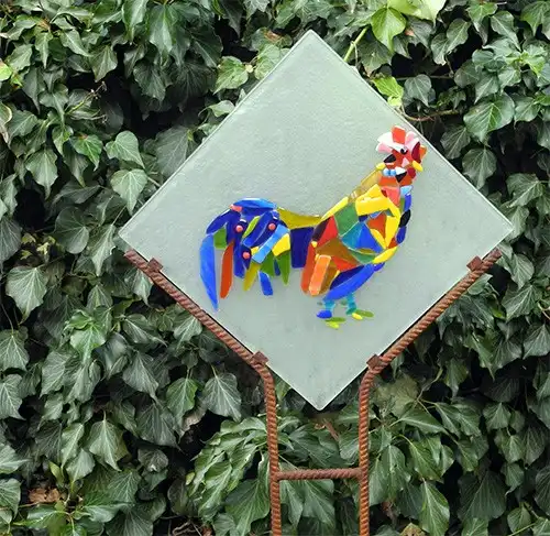 De haan van Lies Roos als lichtvanger, gefuseerd glas in een tuinframe