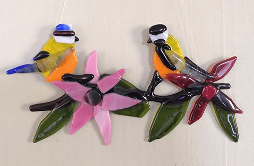Raamhanger van gefuseerd glas: twee vogels op een tak met bloemen, gemaakt door Marjolein Doets