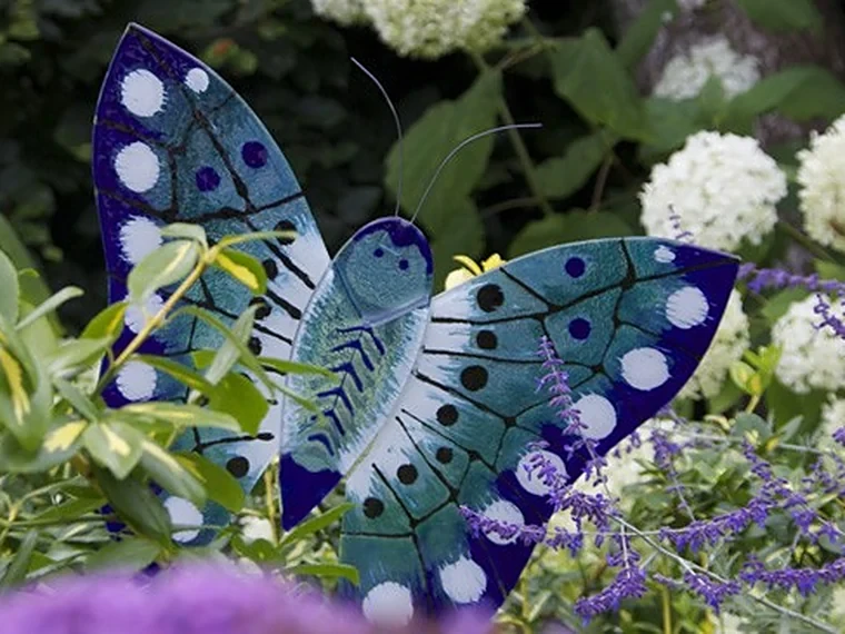 Blauwe glazen vlinder tussen de bloemen in de tuin